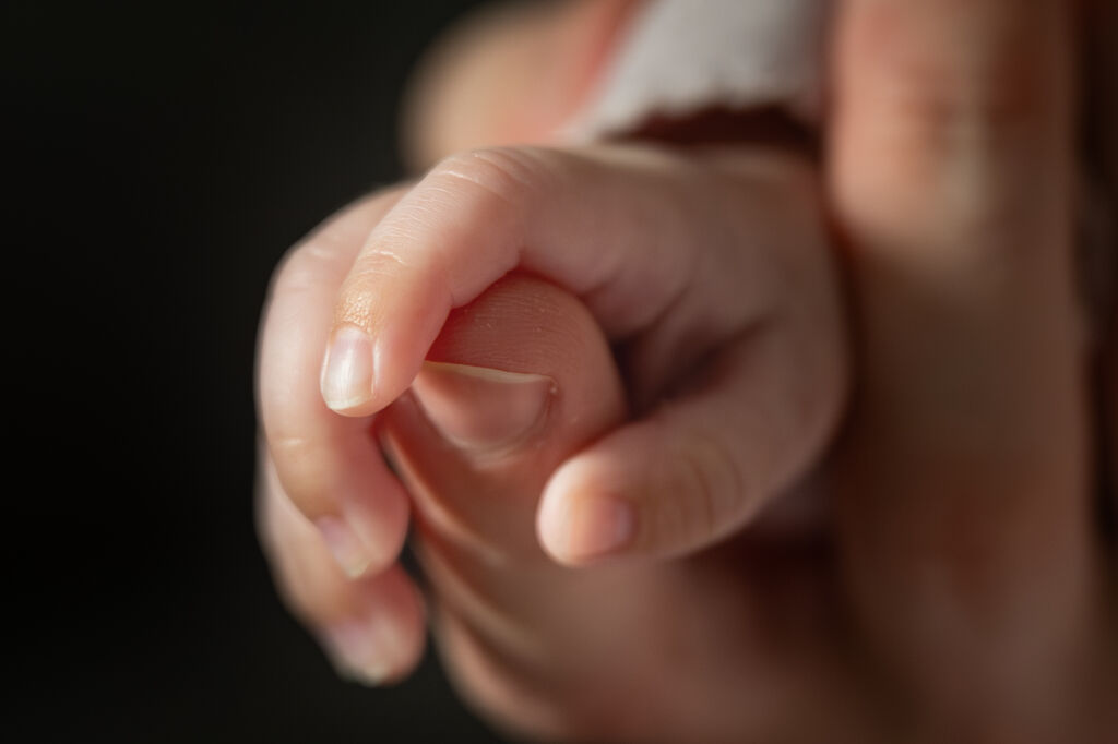 Detailn&iacute; z&aacute;běr na sevřenou pěstičku novorozence s drobn&yacute;mi prst&iacute;čky.