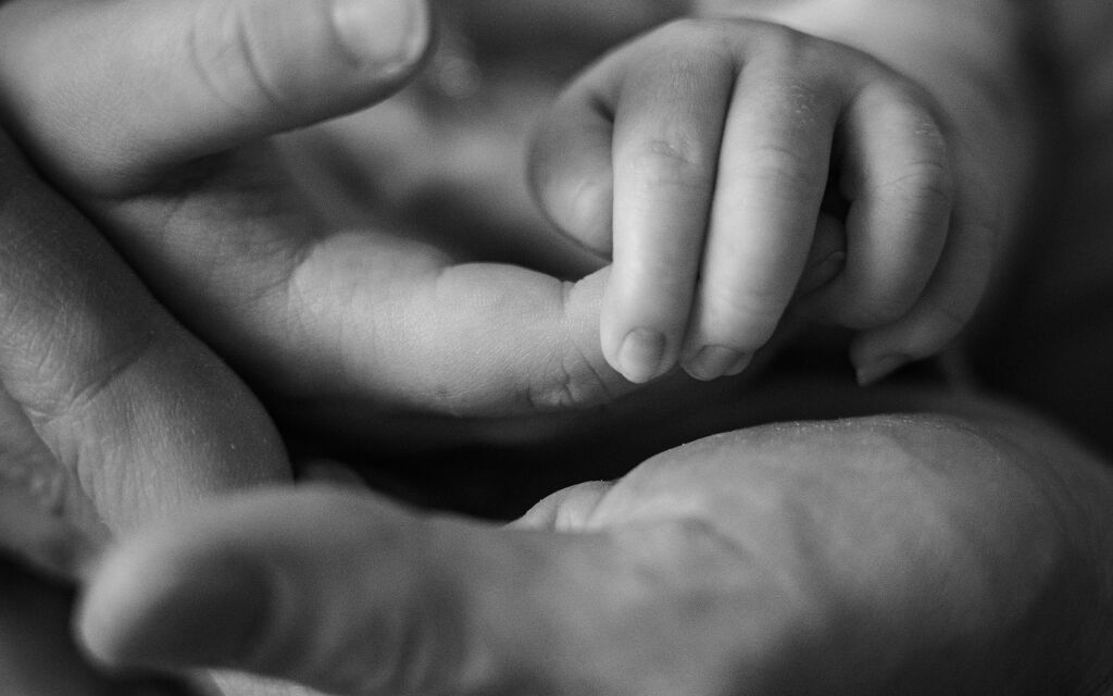 Detail ručičky novorozence drž&iacute;c&iacute; prst rodiče - černob&iacute;l&aacute; newborn fotografie.