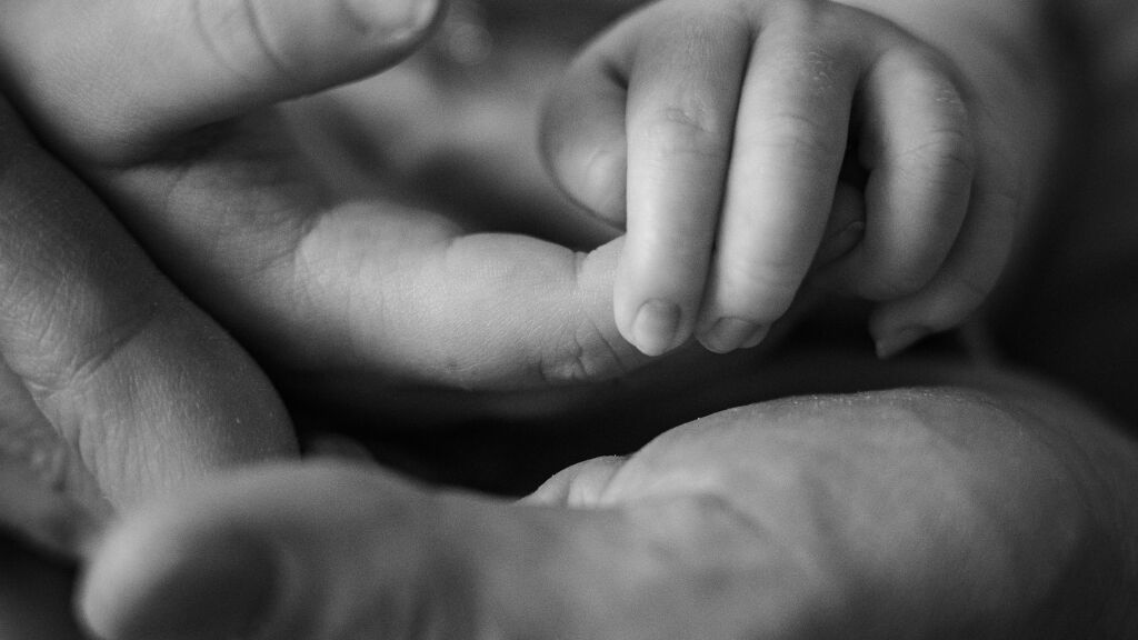 Detail ručičky novorozence drž&iacute;c&iacute; prst rodiče - černob&iacute;l&aacute; newborn fotografie.