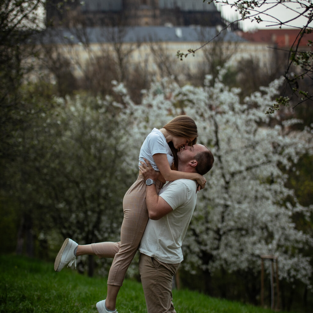 Muž zved&aacute; partnerku do n&aacute;ruče s Pražsk&yacute;m hradem v pozad&iacute; - p&aacute;rov&eacute; focen&iacute;.