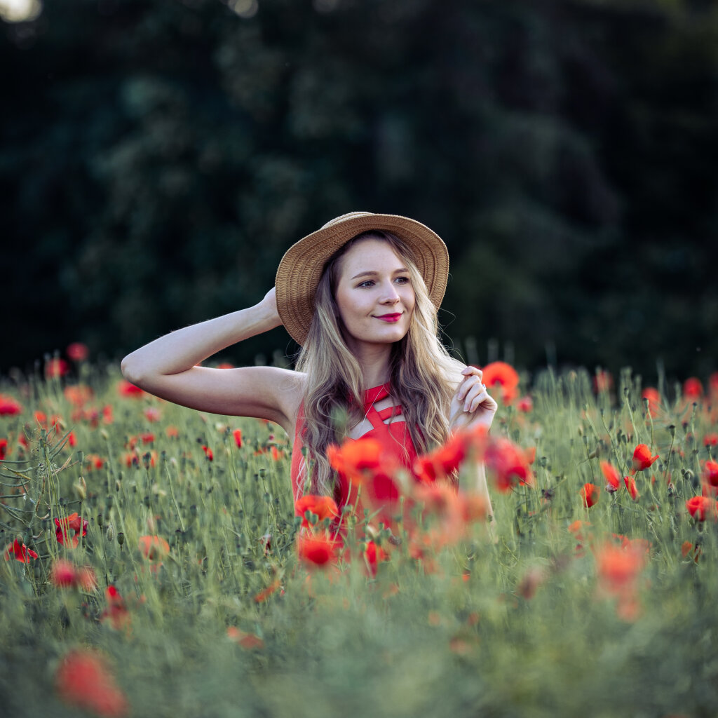 Portr&eacute;t ženy se slaměn&yacute;m kloboukem v rozkvetl&eacute;m makov&eacute;m poli.
