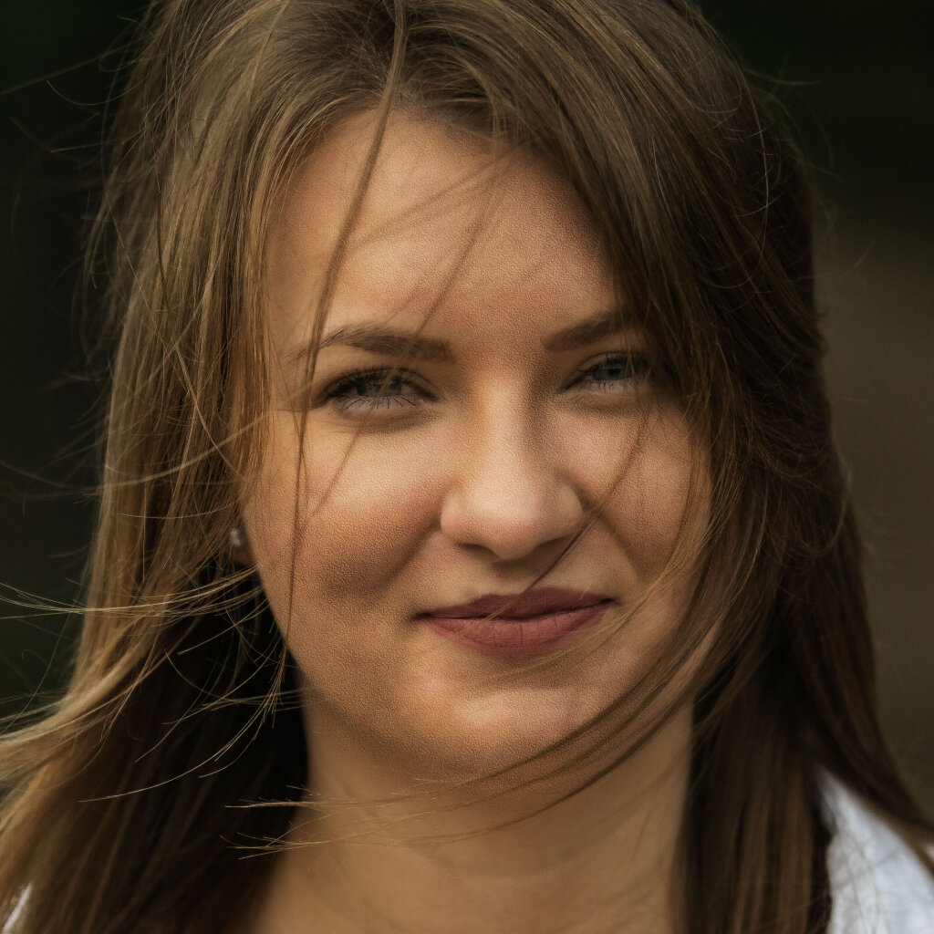 Detailn&iacute; portr&eacute;t usm&iacute;vaj&iacute;c&iacute; se ženy s vlasy ve větru v př&iacute;rodn&iacute;m světle.