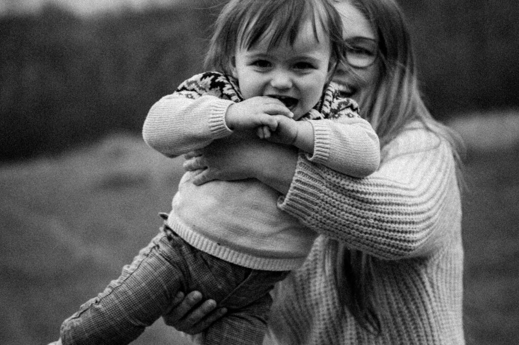 Maminka se toč&iacute; s rozesm&aacute;t&yacute;m batoletem v n&aacute;ruč&iacute; &ndash; černob&iacute;l&aacute; fotografie.