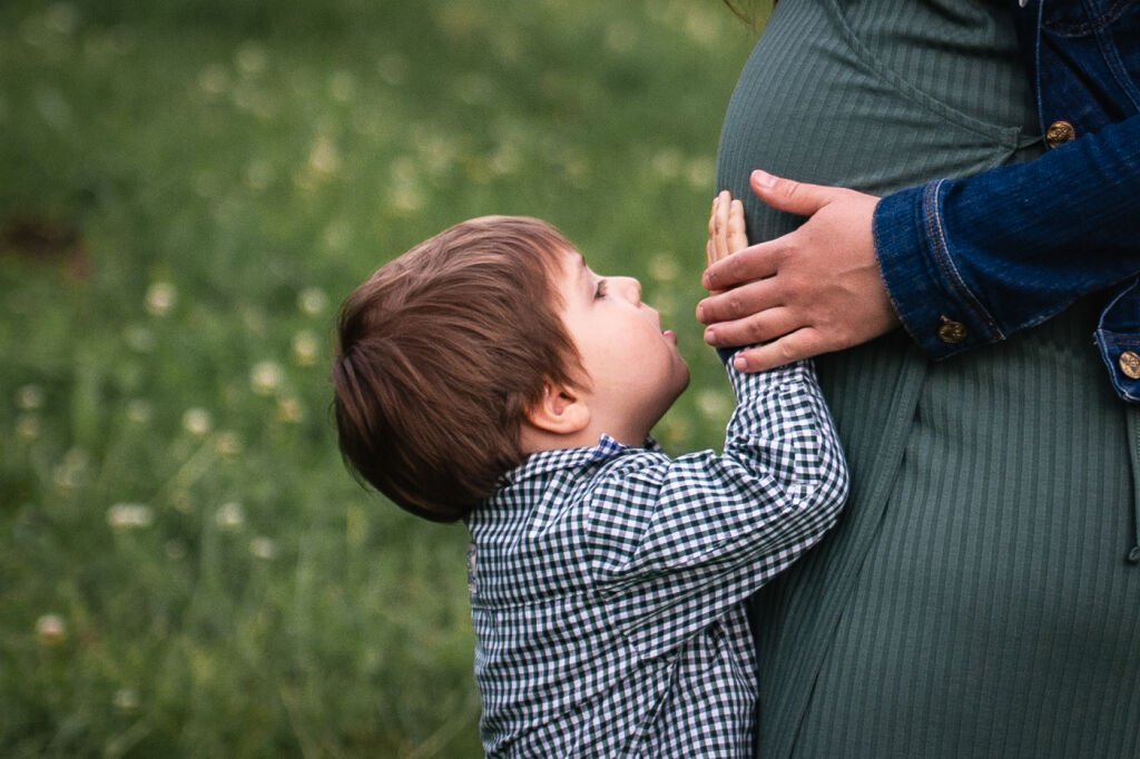 Mal&yacute; synek se dot&yacute;k&aacute; bř&iacute;&scaron;ka těhotn&eacute; maminky a d&iacute;v&aacute; se na ni.